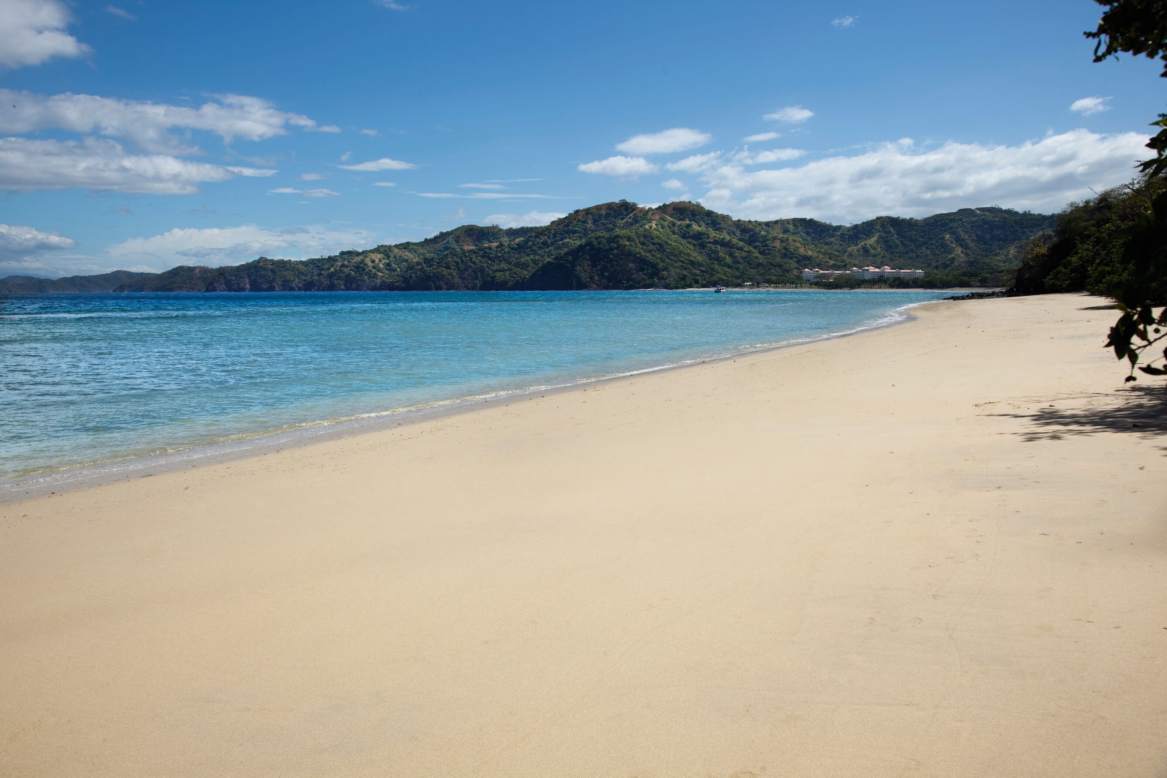 A beach with clear blue water and a sandy shore.