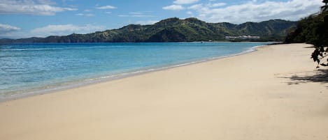A beach with clear blue water and a sandy shore.