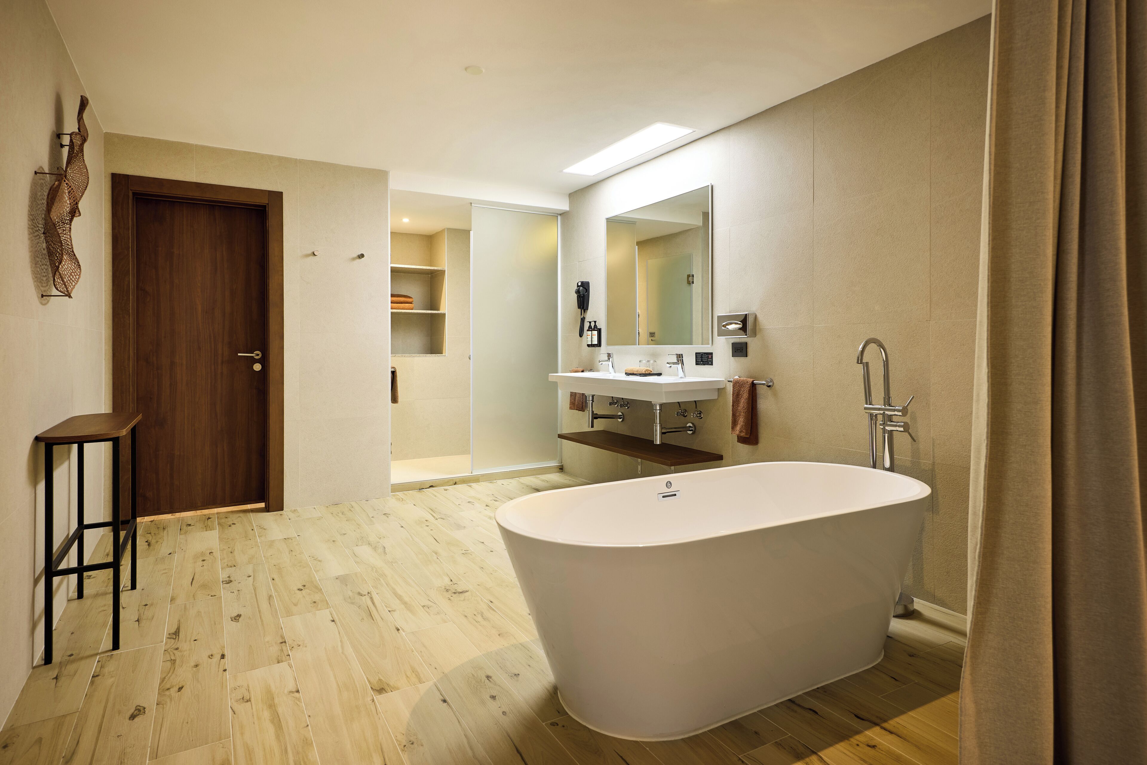 Une salle de bain moderne avec une baignoire sur pieds, un meuble-lavabo avec un miroir et un plancher en bois.