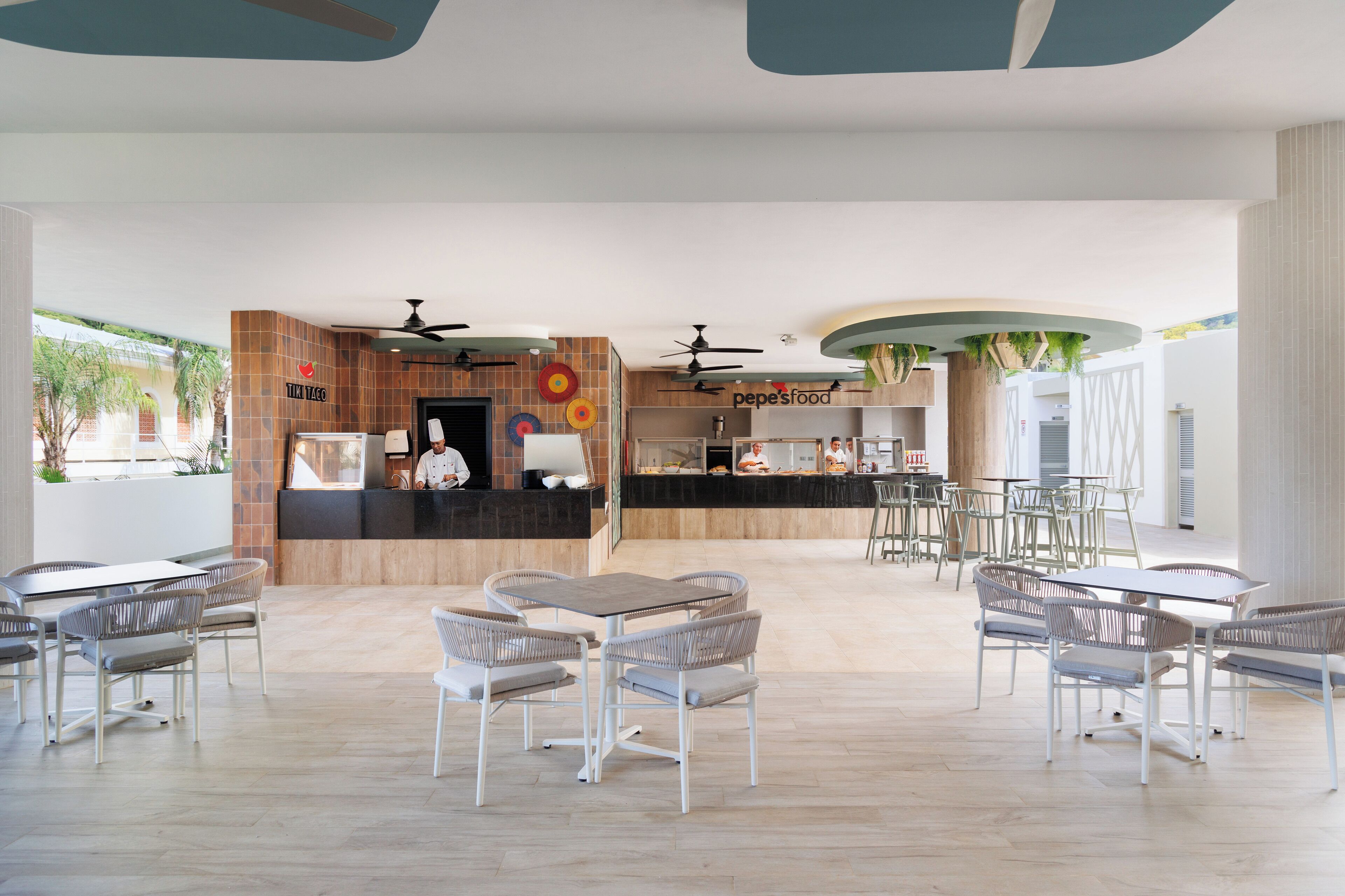 A modern restaurant with a counter, seating area, and ceiling fans.