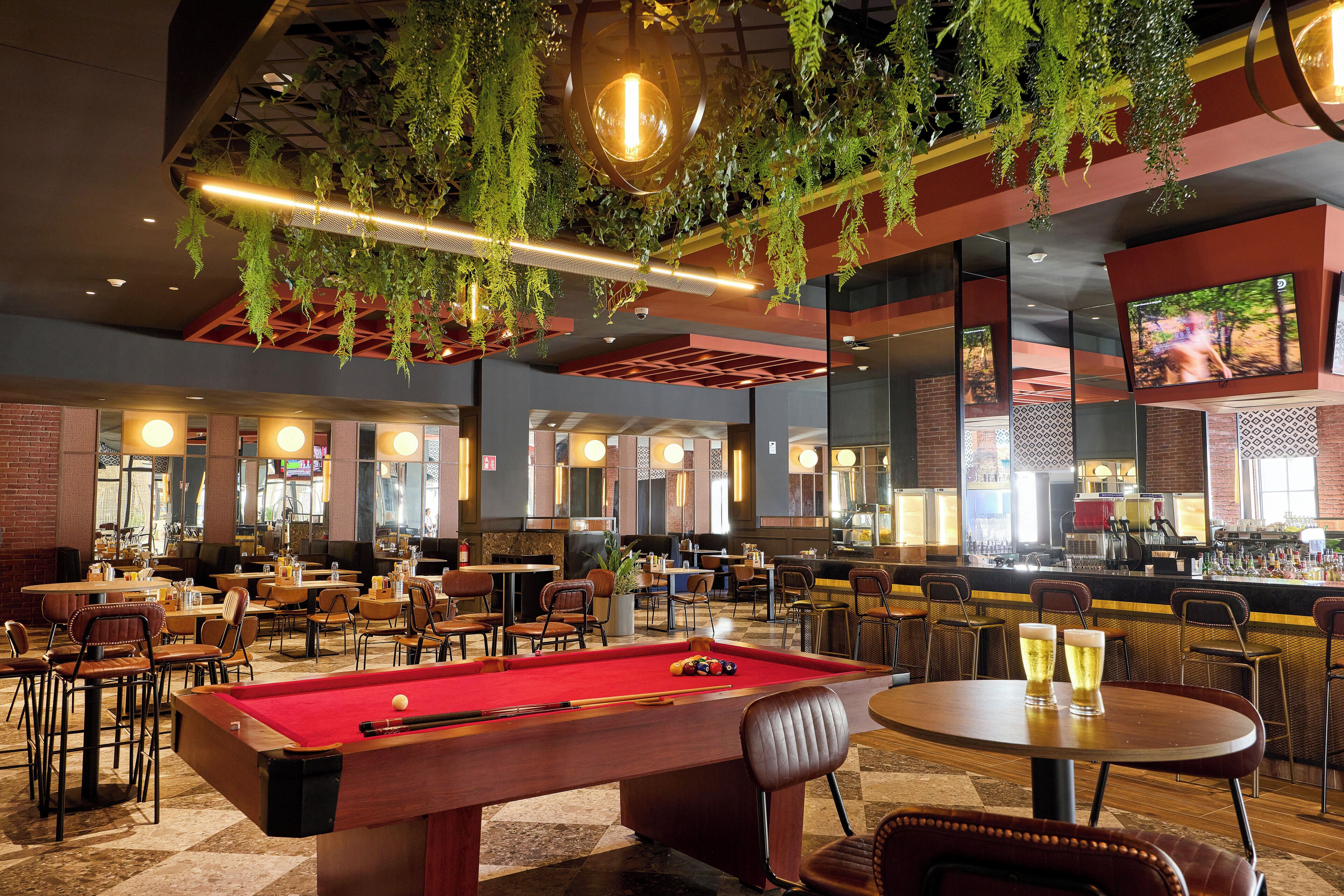 A billiards table, multiple seating areas, and a bar with a television screen.