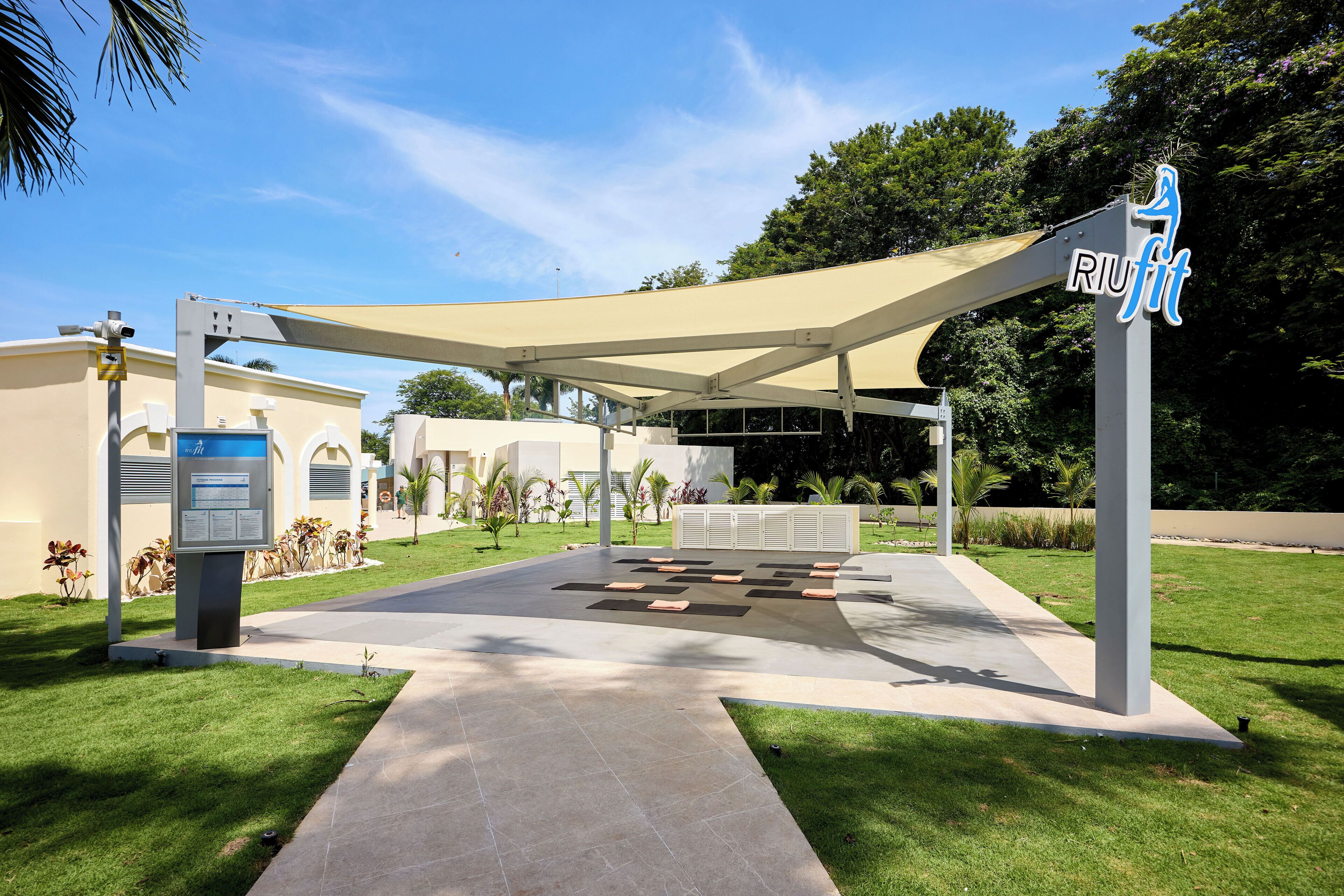 An outdoor area with a covered seating area, a sign with 'RUIFIT' logo, and a building in the background.