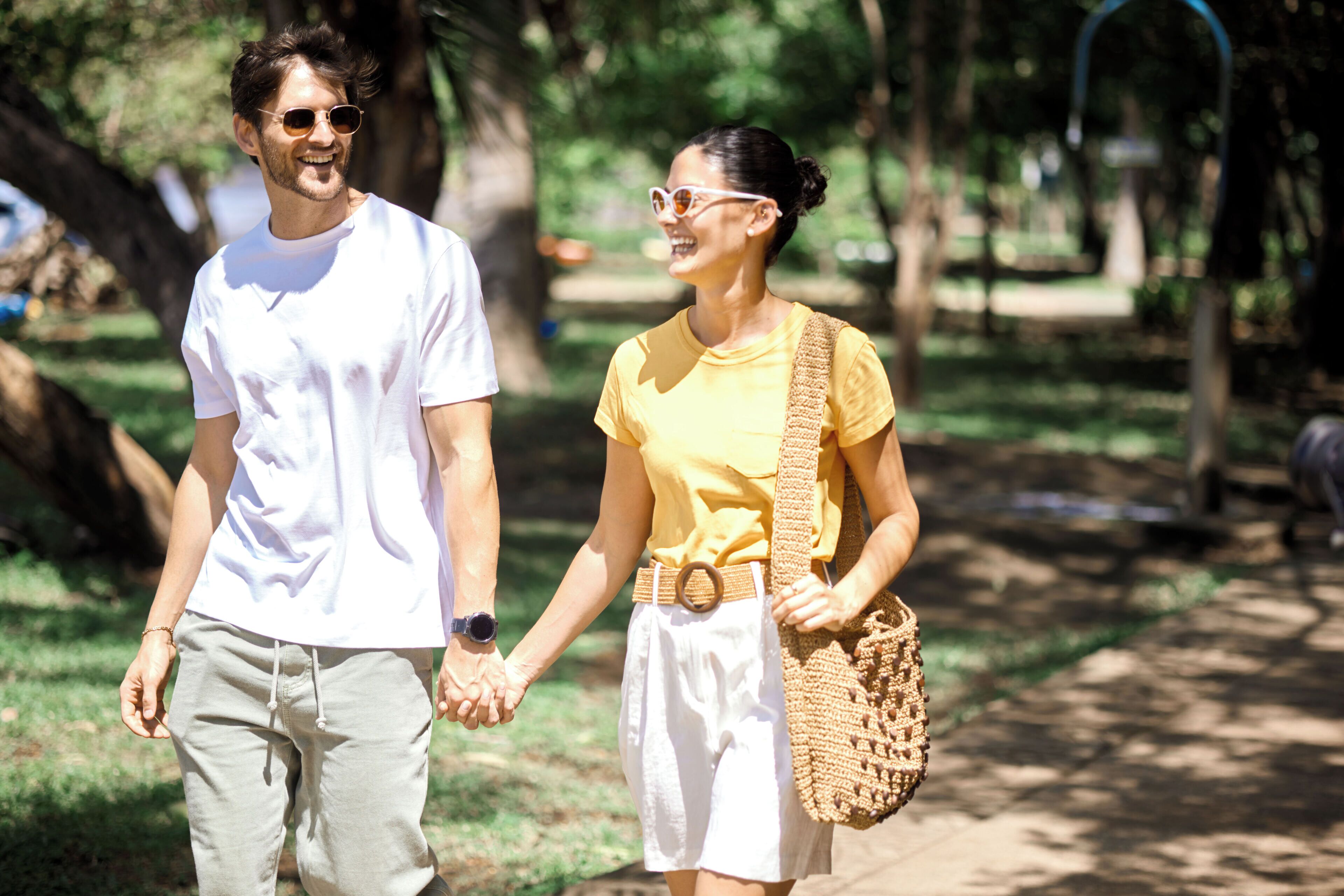 Two people walking hand in hand in a park.