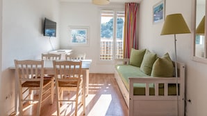 A room with a bed, a desk, chairs, a television, and a window with curtains. - Vacanceole Residence L'Ile d'Or (La Londe-les-Maures)