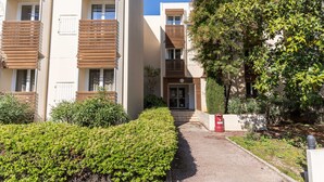 A modern apartment building with balconies, a pathway, and a garden area. - Vacanceole Residence L'Ile d'Or (La Londe-les-Maures)