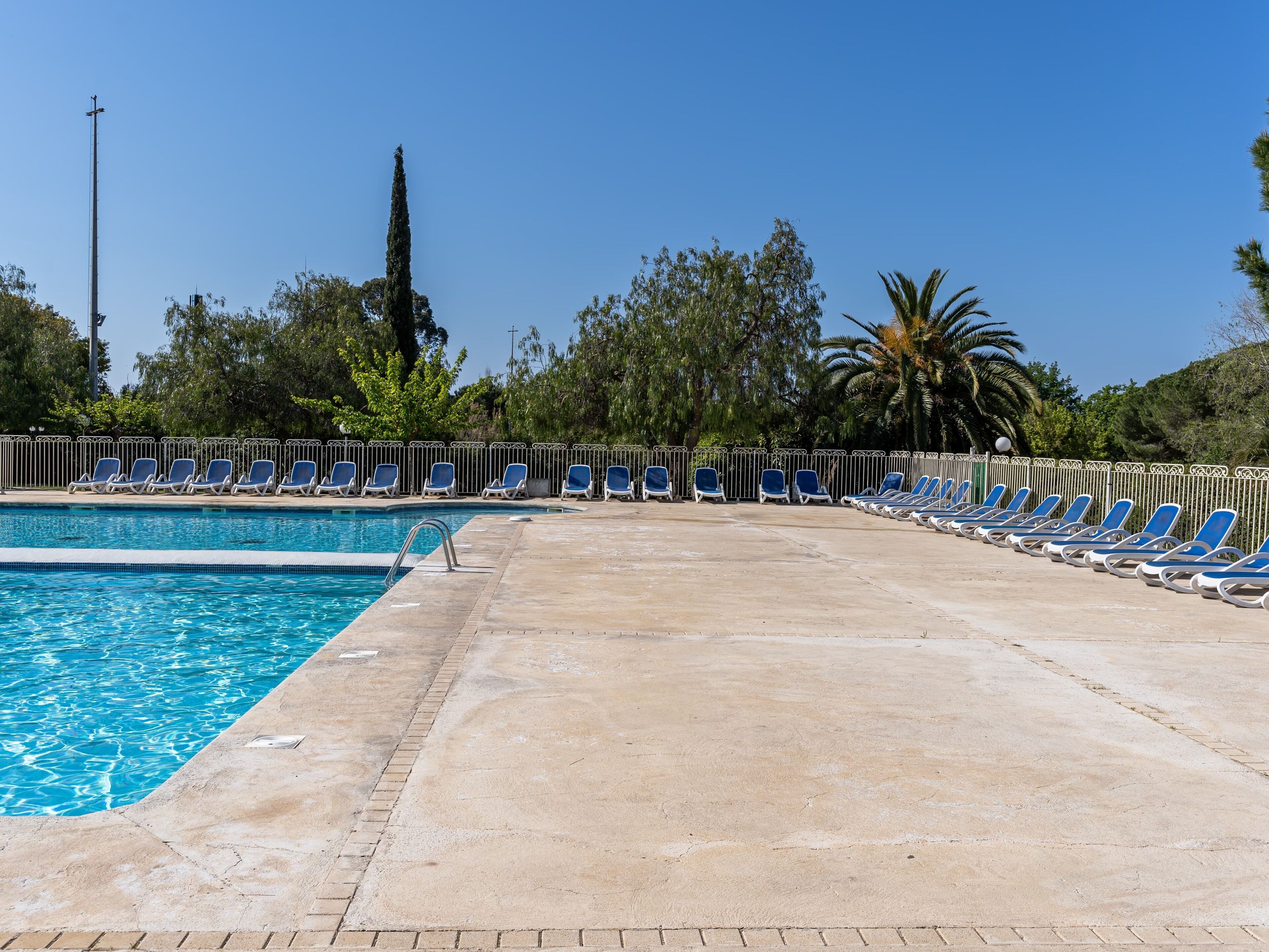 Una piscina con sillones de descanso y un cielo despejado.