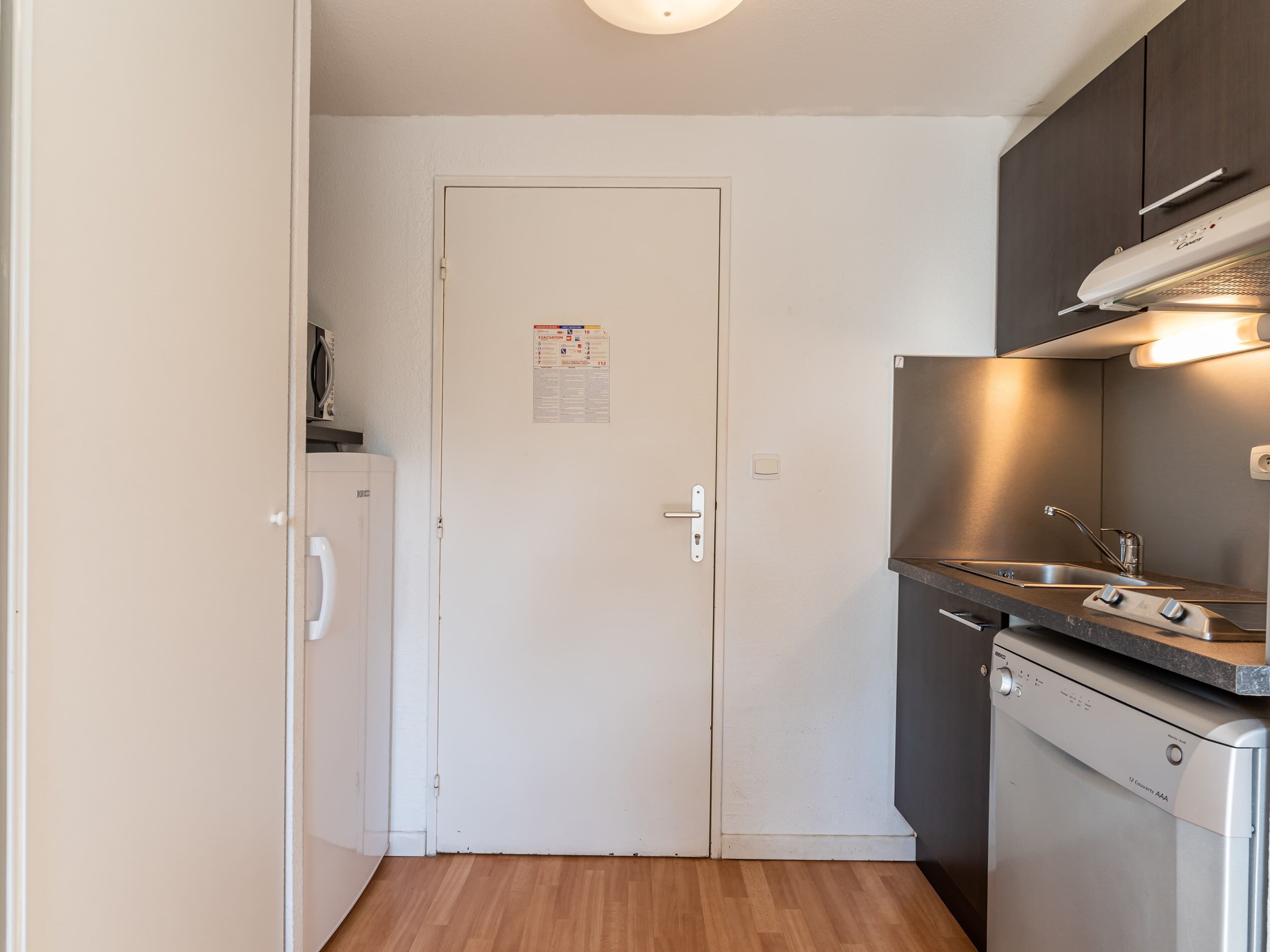 A compact kitchen with a white refrigerator, a dishwasher, and a stove.