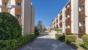 A modern residential building with a paved driveway and well-maintained hedges. - Vacanceole Residence L'Ile d'Or (La Londe-les-Maures)