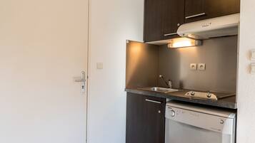 A compact kitchen with a dishwasher, a sink, and dark wooden cabinets.