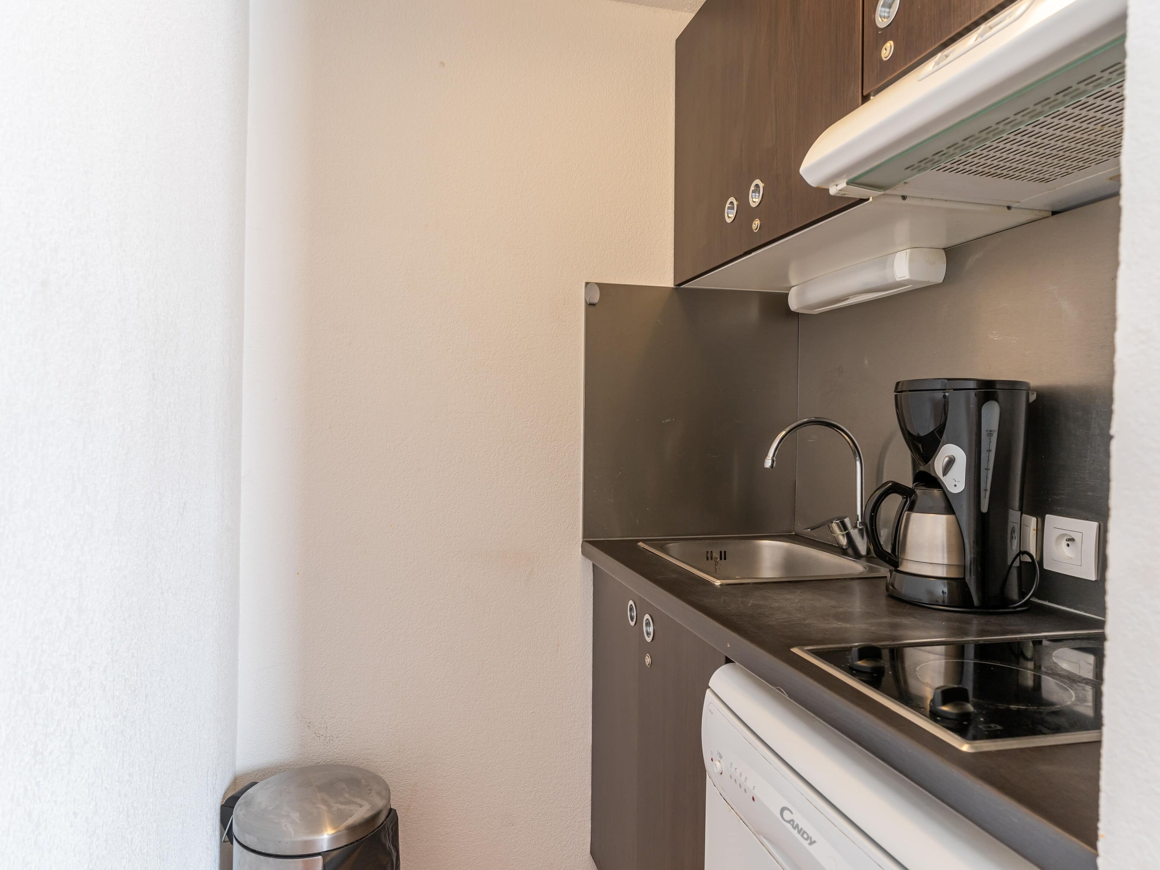 A compact kitchenette with a stainless steel sink, a coffee maker, and a dishwasher.