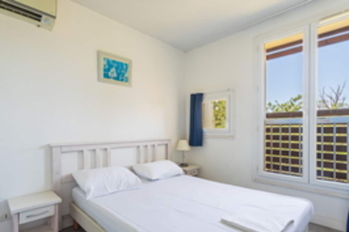 Ein Schlafzimmer mit einem Einzelbett, einem Nachttisch, einem Fenster mit Blick und einer Wand-Klimaanlage.