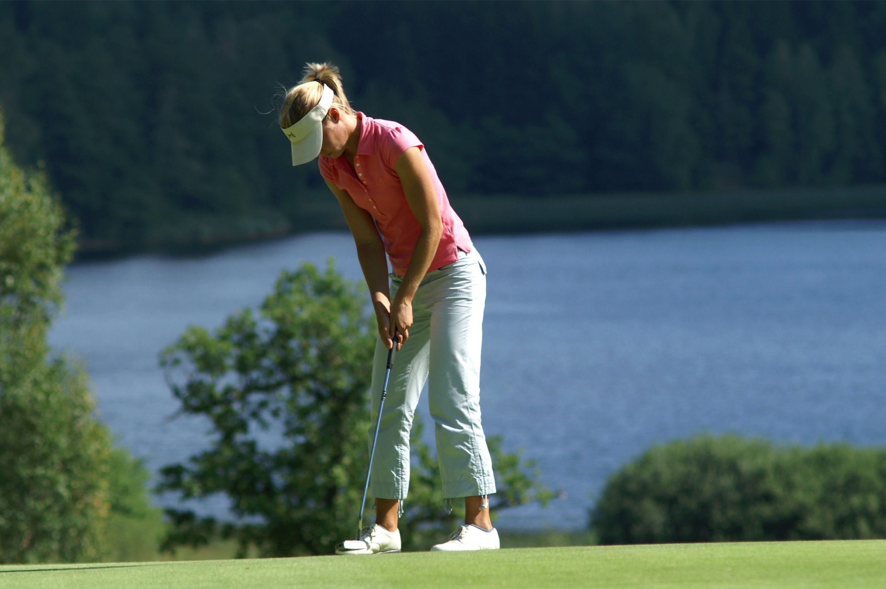 A person on a golf course with a body of water in the background.