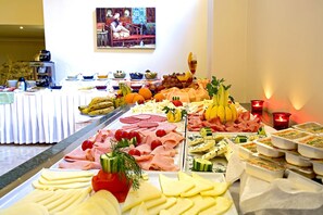 Ein Buffet mit verschiedenen Speisen, darunter Fleisch, Käse und Obst.