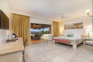 A hotel room with a bed, bedside tables, a desk, a chair, a view of the outdoors, and a painting on the wall.