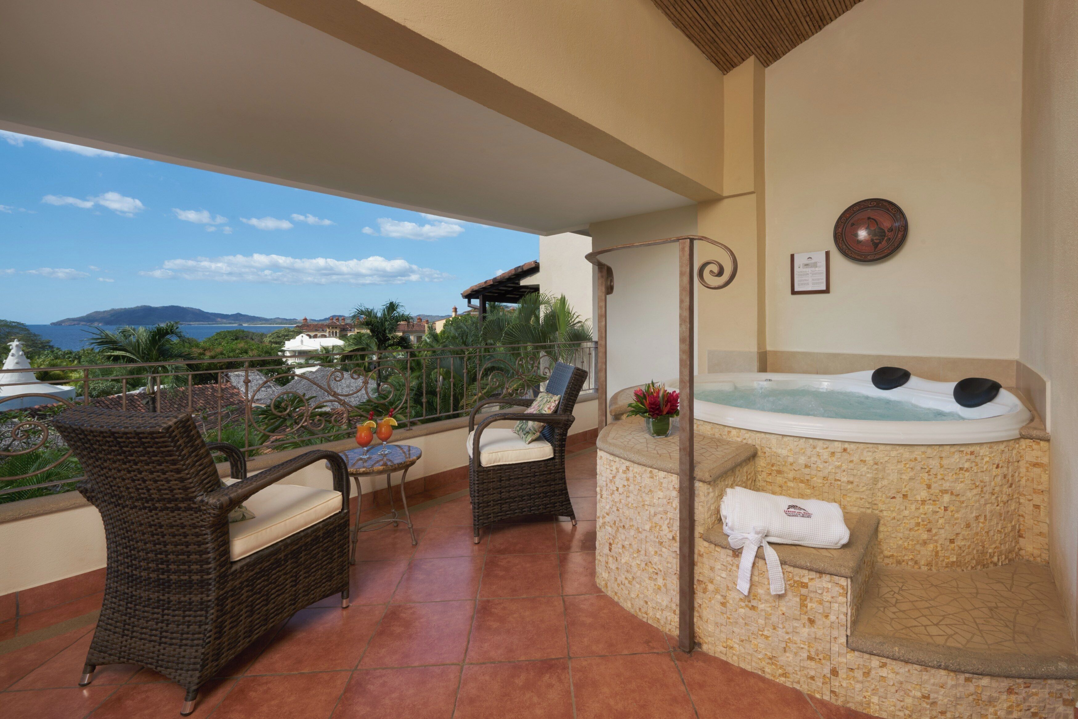 A balcony with wicker furniture, a hot tub, and a view of the sea.