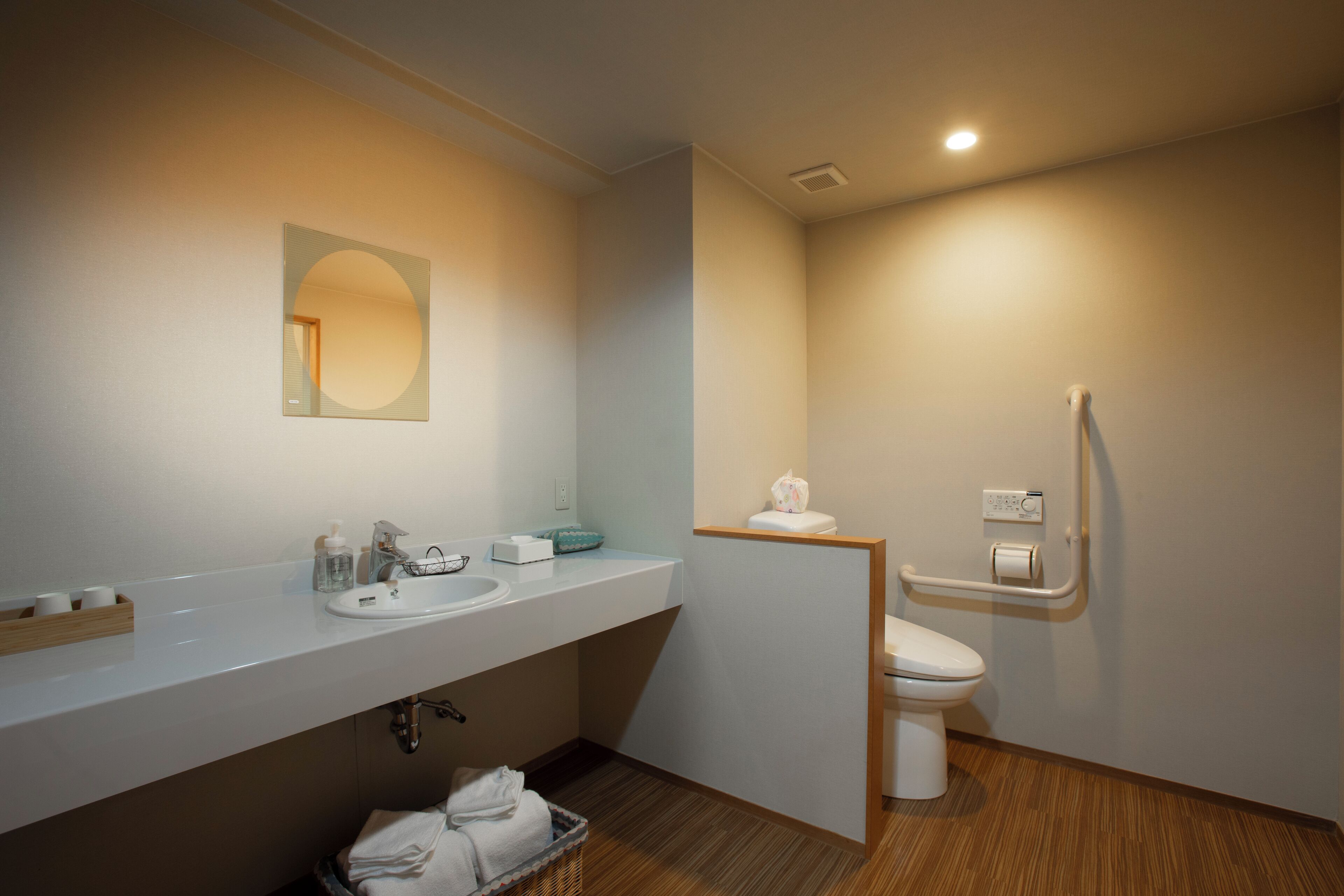 A modern bathroom with a white sink, mirror, and toilet.