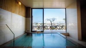 Una piscina interior con vistas a un paisaje urbano a través de amplios ventanales.