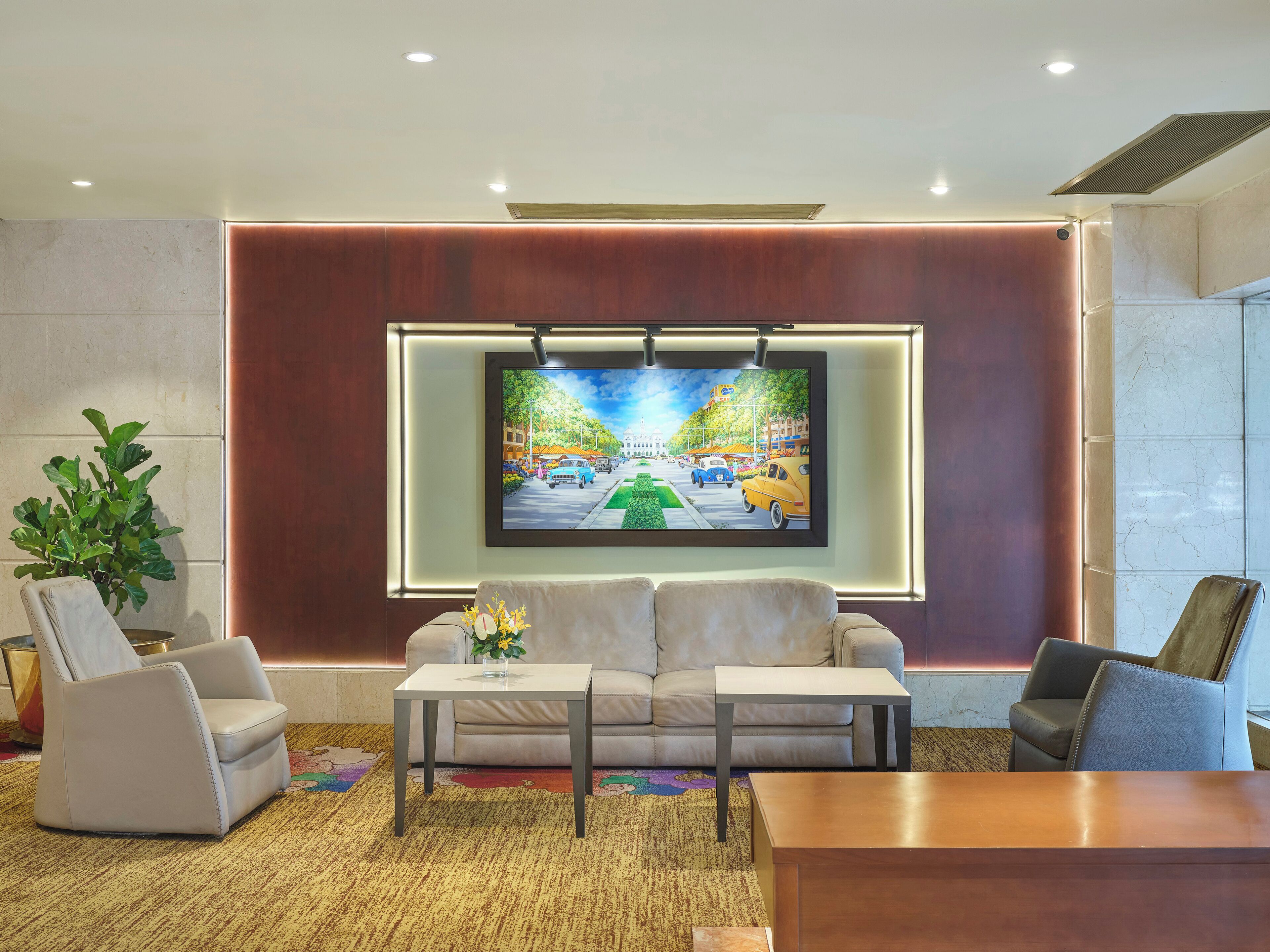 A modern living room with a large TV mounted on a wall, a sofa, two armchairs, and a coffee table.