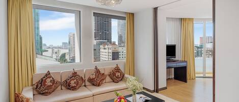 A modern living room with a sofa, coffee table, and large windows offering a city view.