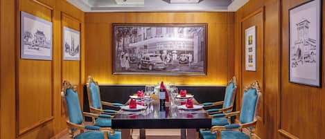 Une salle de conférence avec une grande table, quatre chaises bleues rembourrées et des tableaux encadrés accrochés aux murs.