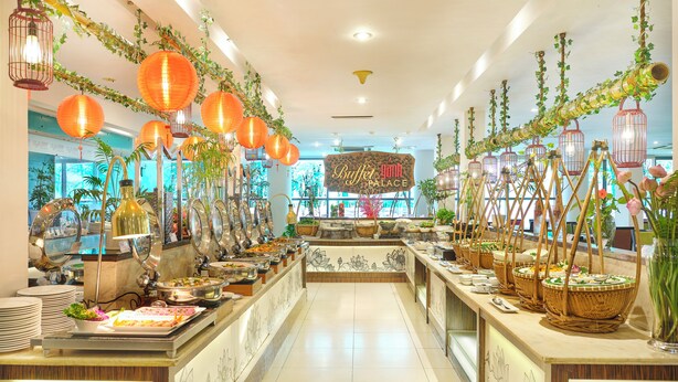 Un espace buffet comprenant plusieurs stands de nourriture, des lanternes suspendues et des plantes décoratives.