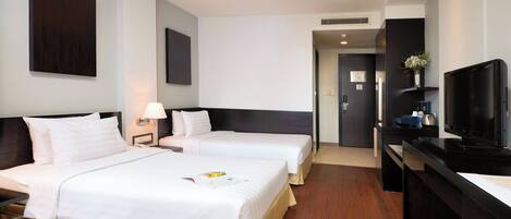 A hotel room with two beds, a desk, a television, and a door leading to a bathroom.