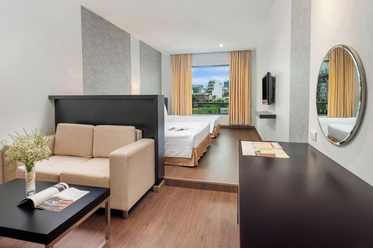 Ein Hotelzimmer mit Sofa, Bett, Schreibtisch und Blick auf die Stadt.