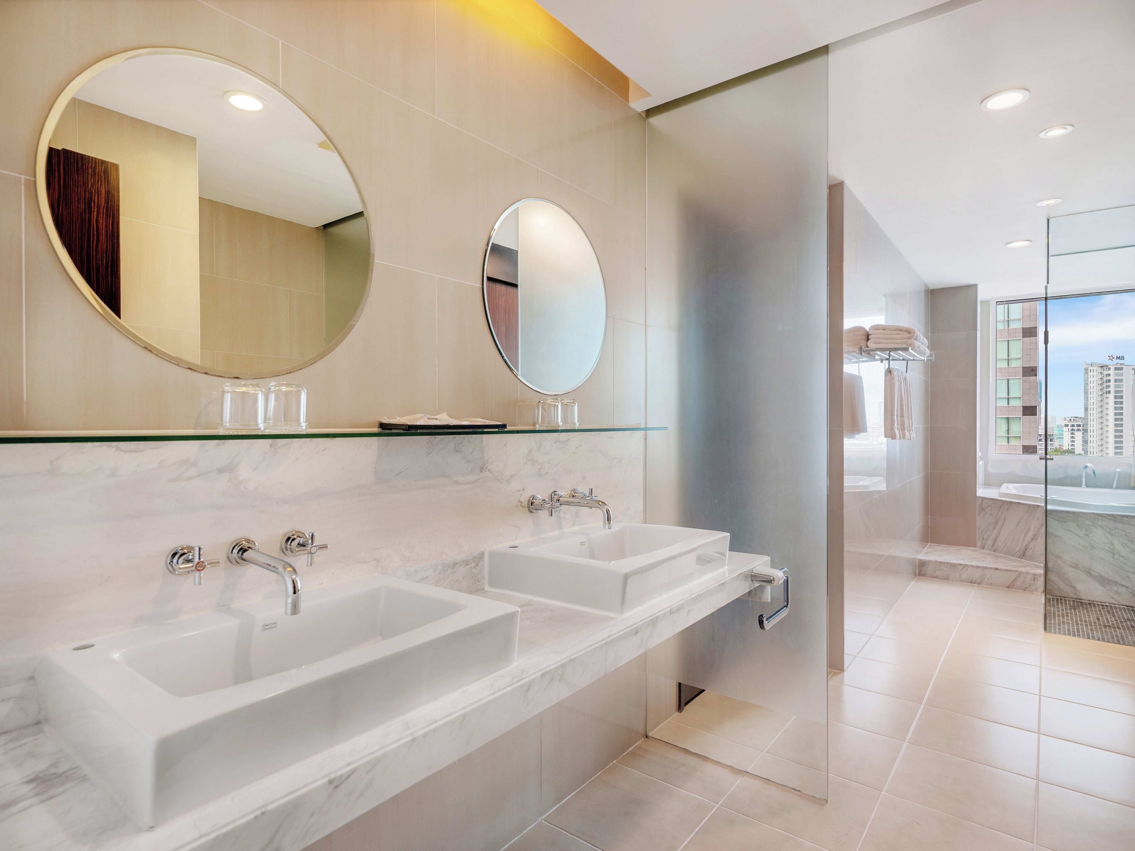 A modern bathroom with two sinks, a glass shower enclosure, and a large mirror.