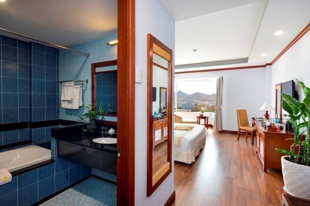 A bathroom with blue tiles, a bathtub, a sink, and a mirror.