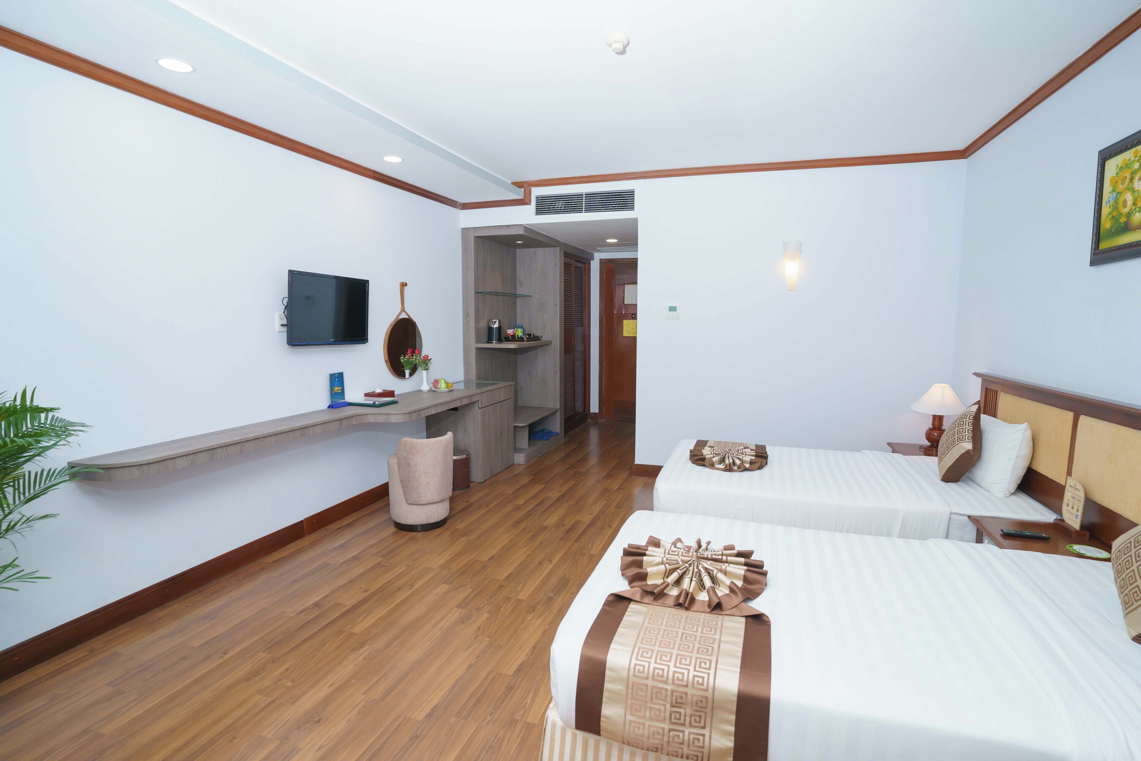 A hotel room with two beds, a desk, a TV, and a small seating area.