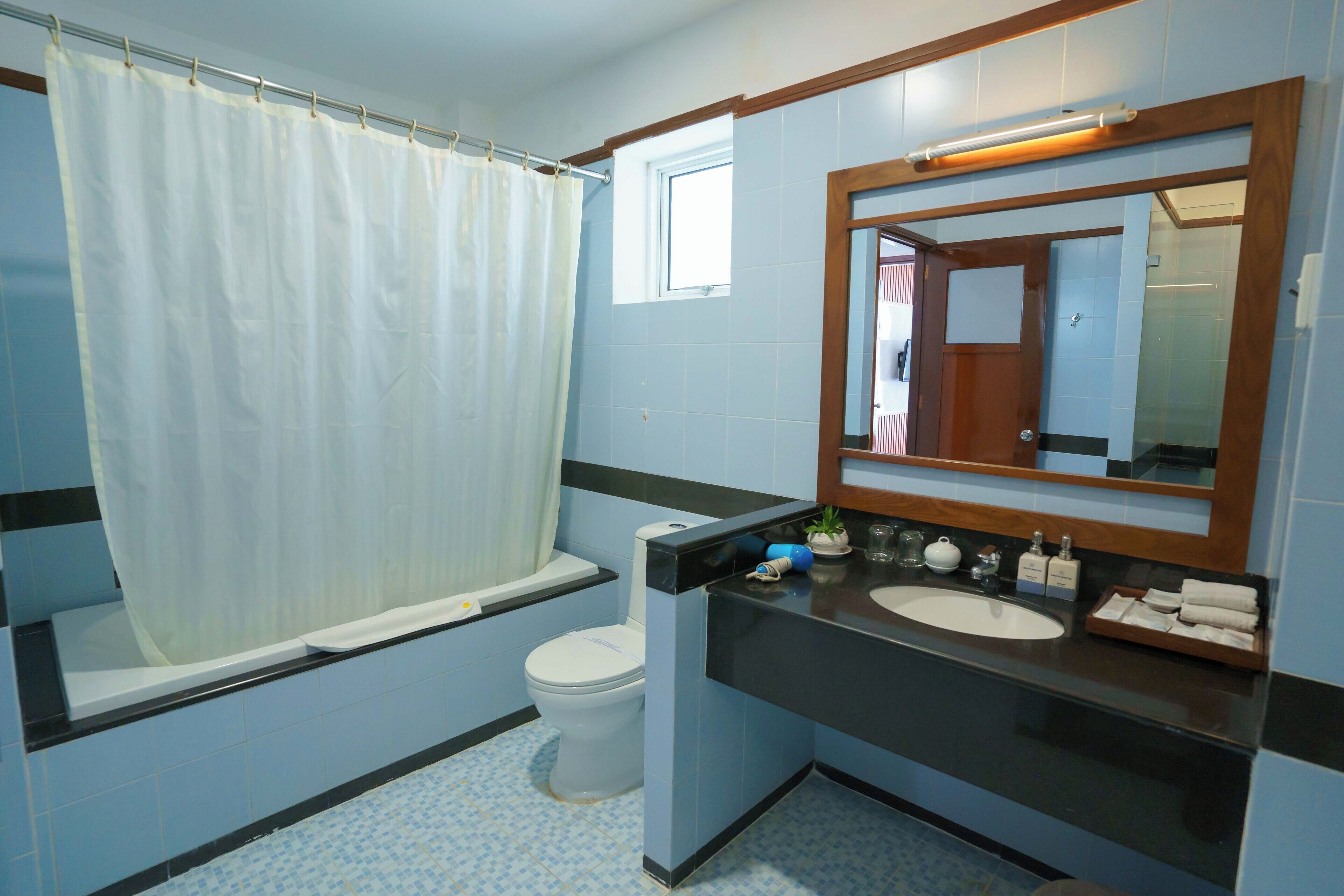 A bathroom with a bathtub, toilet, sink, and mirror.