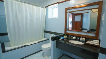A bathroom with a bathtub, toilet, sink, and mirror.