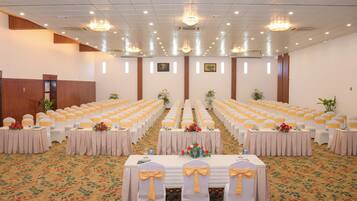 A conference room with rows of tables, each with a white tablecloth and yellow sashes.