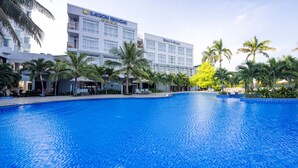 A hotel with a large swimming pool surrounded by palm trees and a modern building. - Saigon Ninh Chu Hotel & Resort (Ninh Chu)