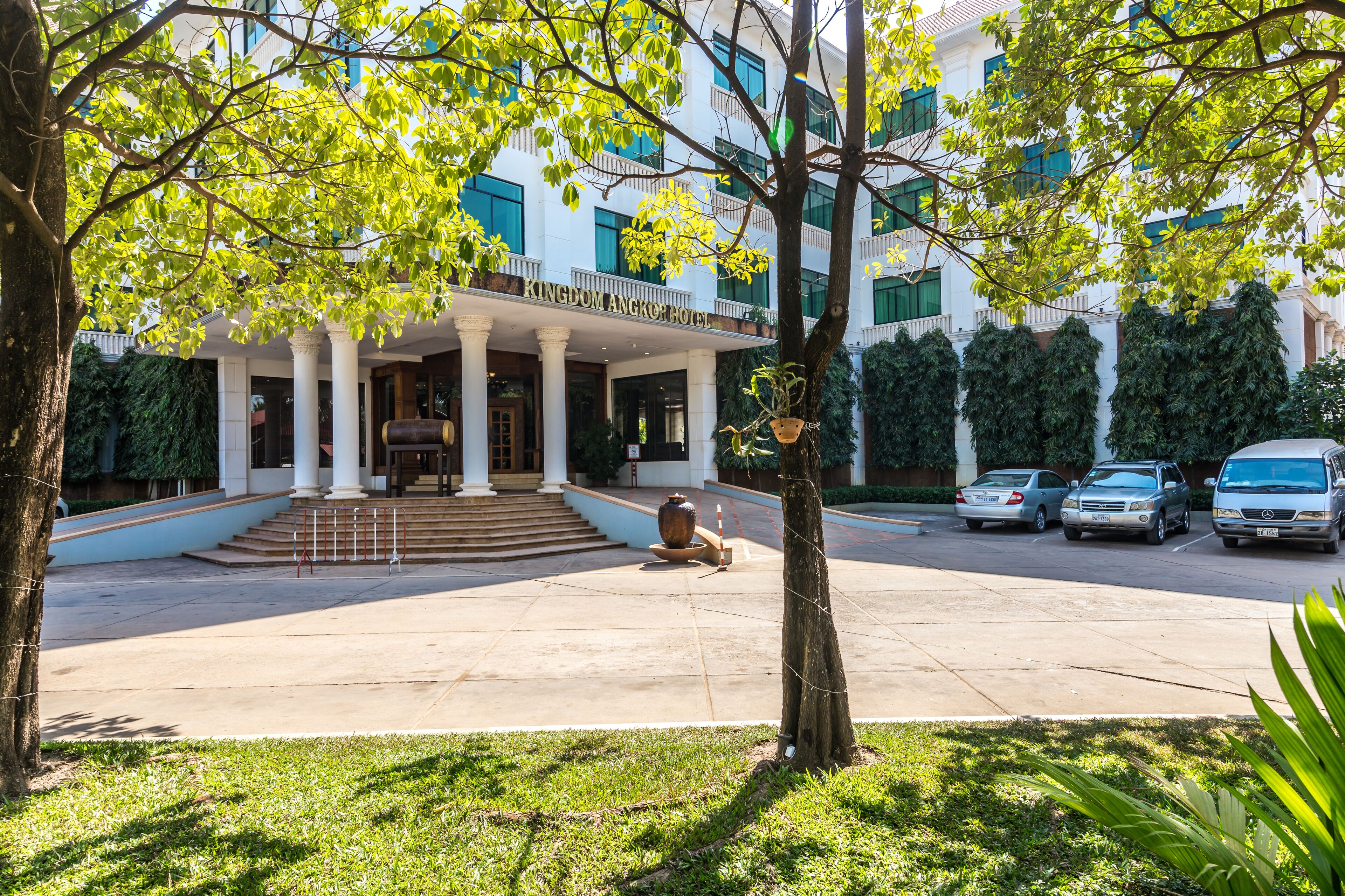A hotel entrance with a covered porch, columns, and a large vase.
