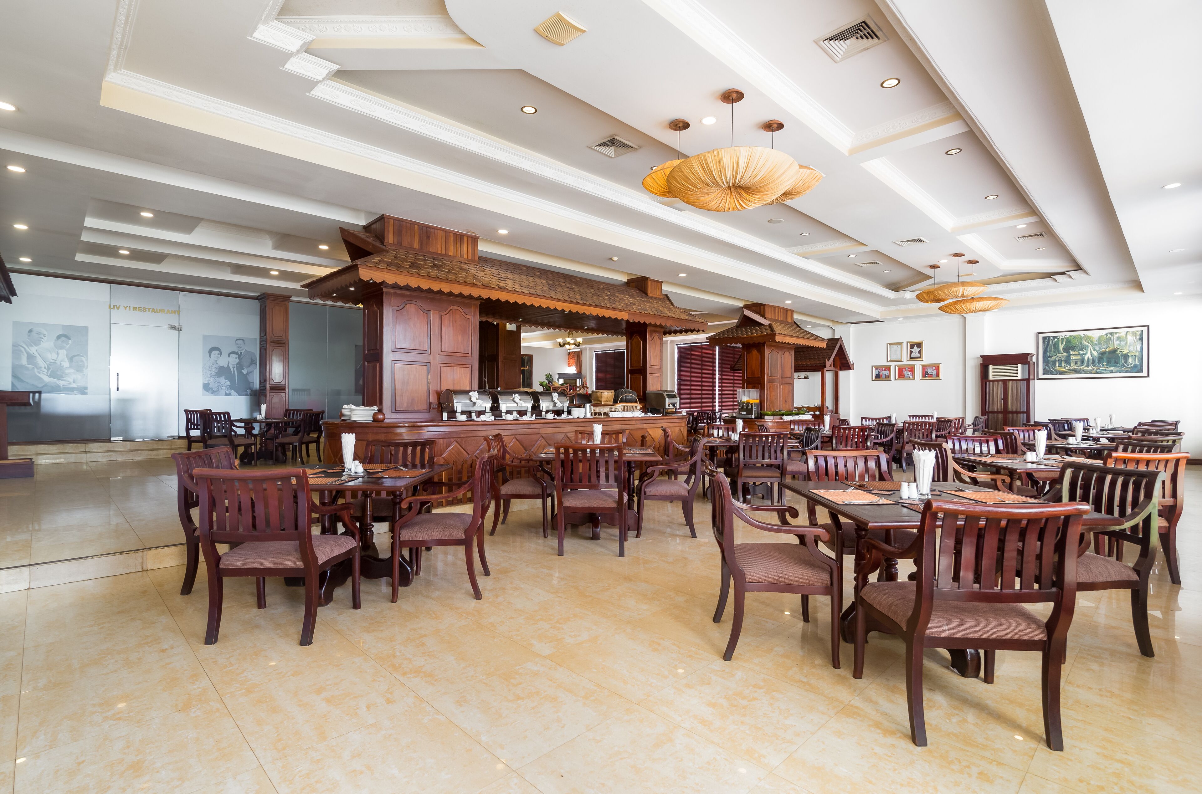 Uma ampla área de refeições com mesas e cadeiras de madeira, um bar e um design de teto moderno.