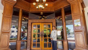 A man standing in front of a wooden entrance with a chandelier and glass doors. - Kingdom Angkor Hotel (Siem Reap)