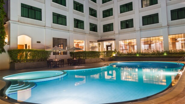 A hotel with a large indoor swimming pool, multiple balconies, and outdoor seating areas. - Kingdom Angkor Hotel (Siem Reap)