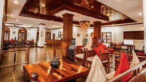 A spacious lobby with wooden furniture, a reception desk, and a chandelier. - The Suite By Royal Crown Hotel (Siem Reap)