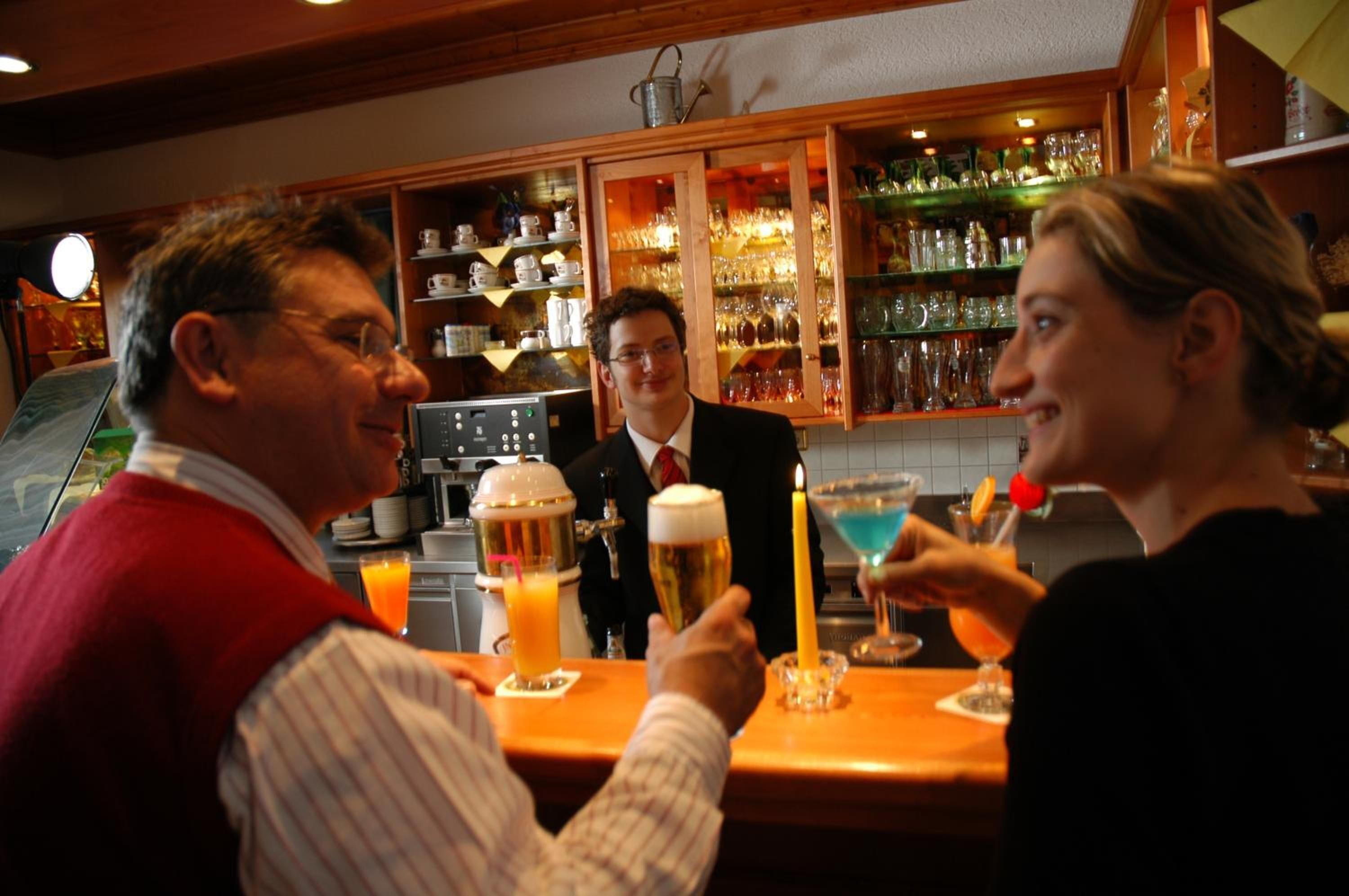 A bar area with a counter, glasses, and bottles.