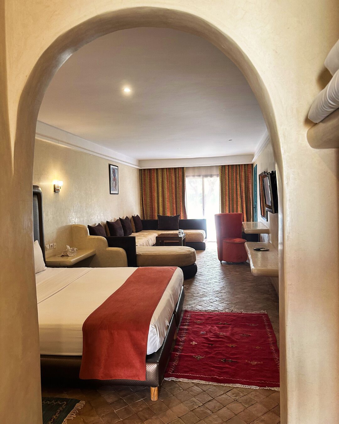 A hotel room with a large bed, a sofa, a chair, and a small table.