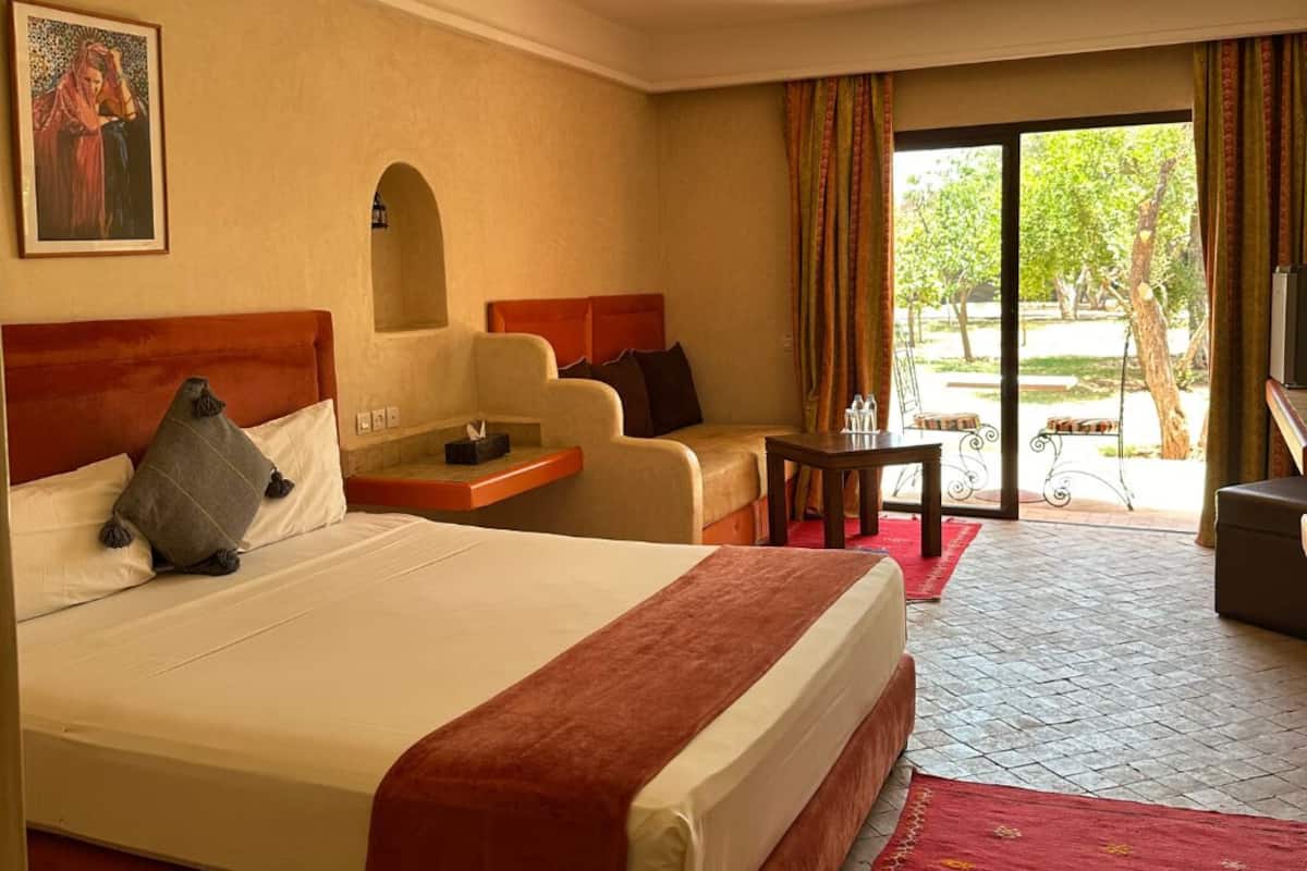 Una habitación de hotel con una cama grande, un sofá, una mesita y un televisor.