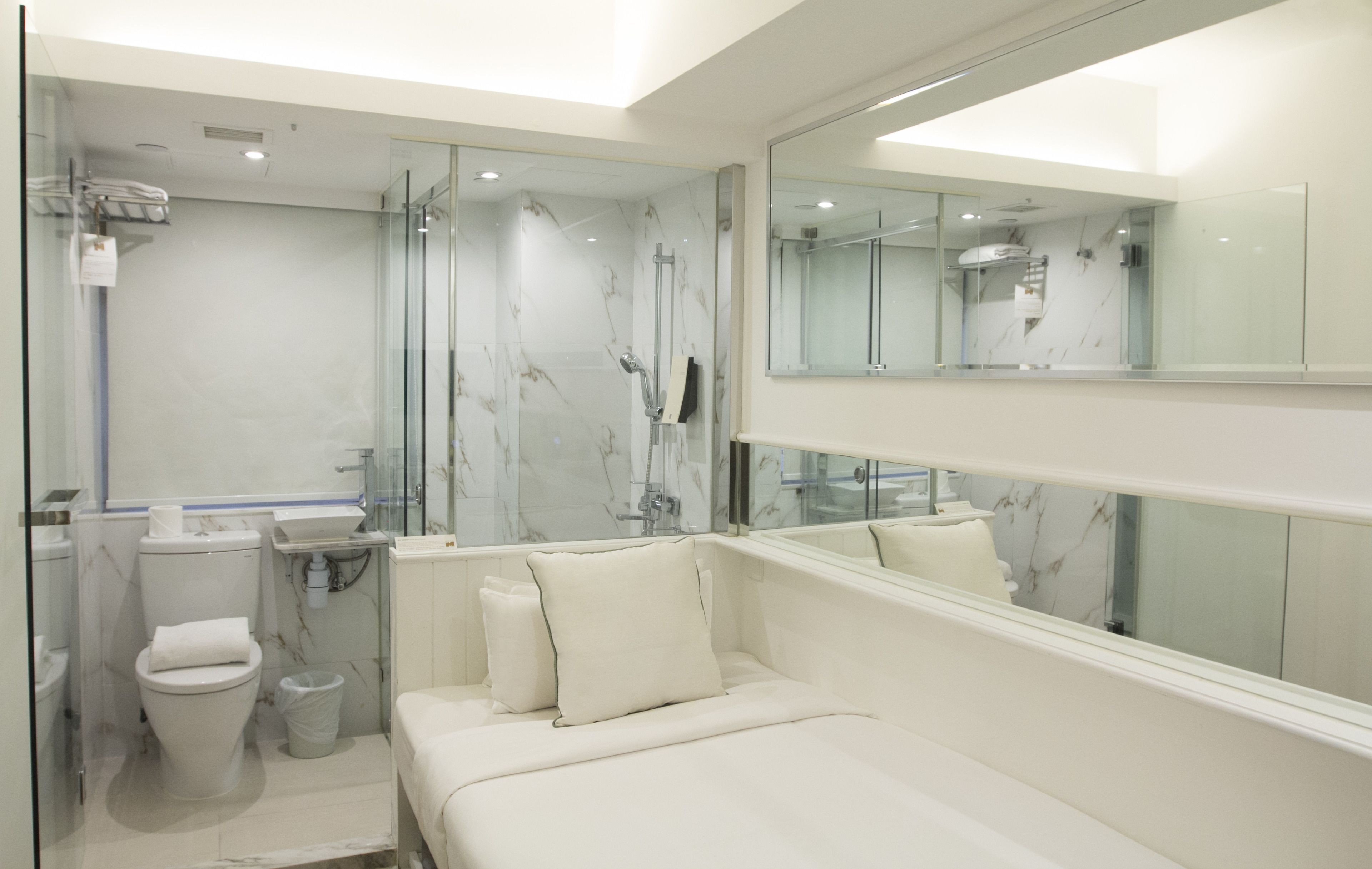 A modern bathroom with a glass shower enclosure, a toilet, a sink, and a large mirror.