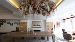 Un saló modern amb una gran taula de menjador de fusta, una llar de foc i un ampli arranjament floral penjant del sostre.