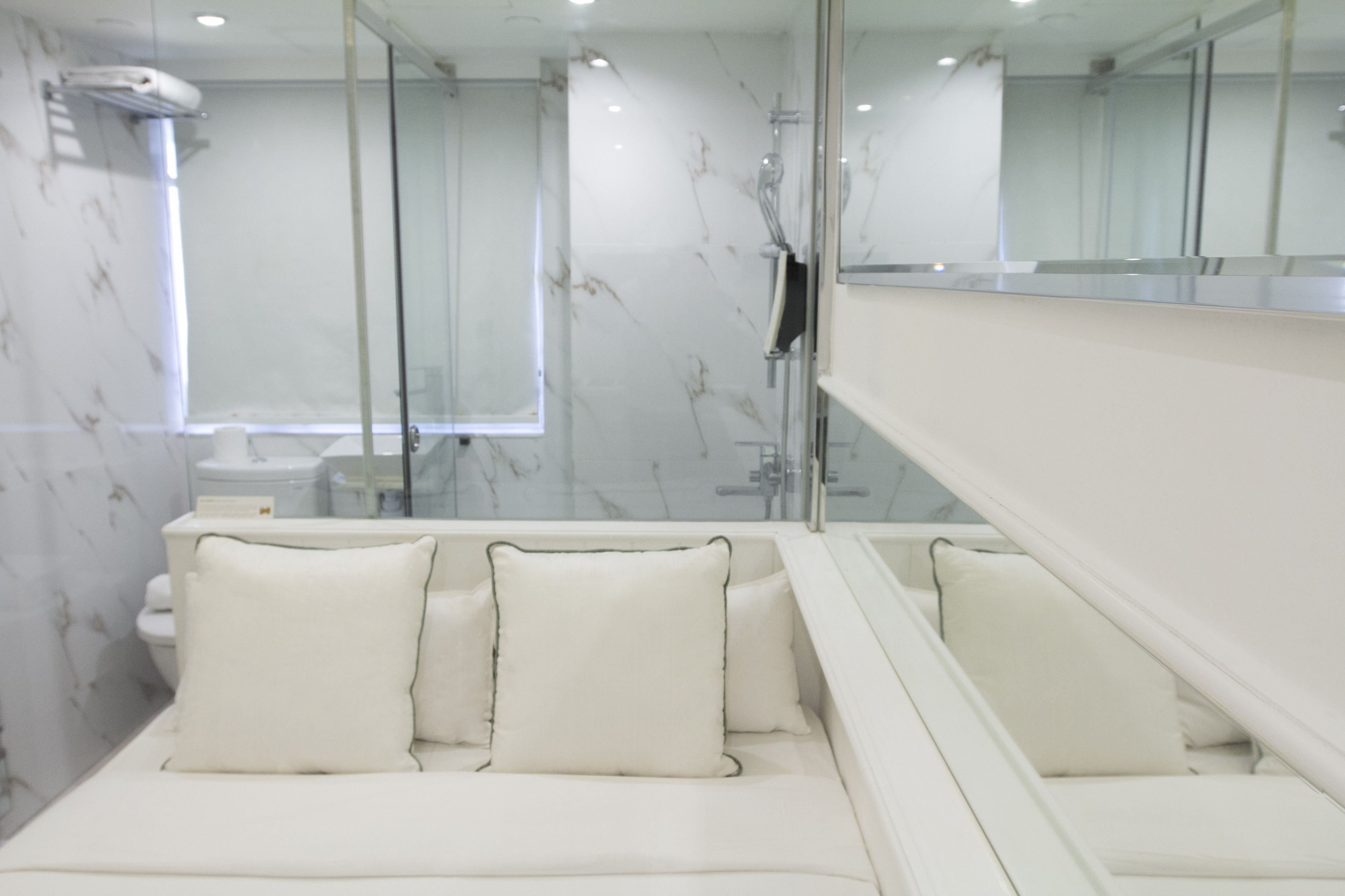 A modern bathroom with a glass shower enclosure, a white bathtub, and a large mirror.