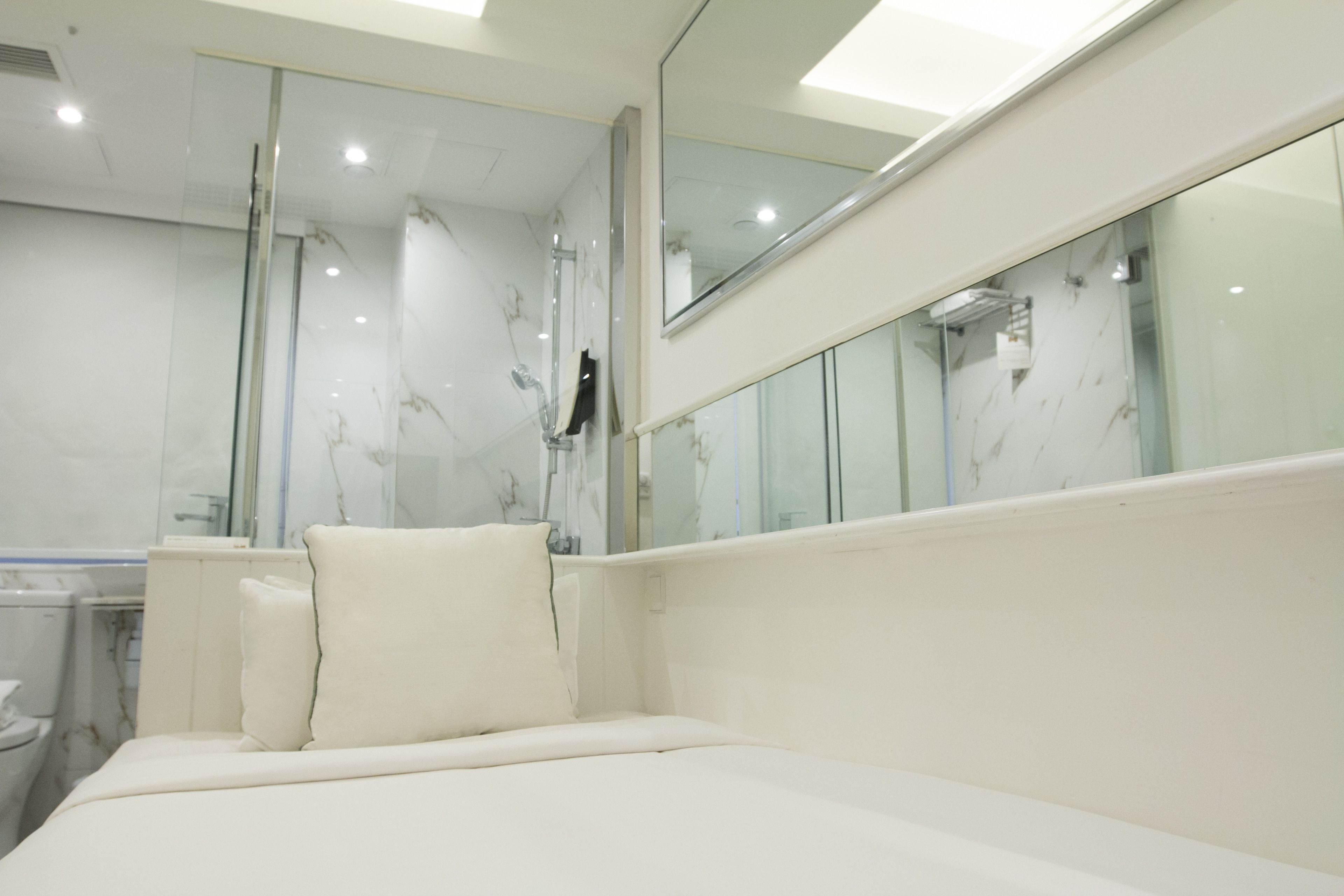 Une salle de bain moderne avec une douche à l’italienne en verre, une baignoire blanche et un grand miroir.