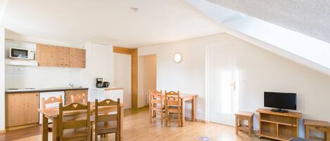 A compact living space with a kitchen, dining area, and a TV.