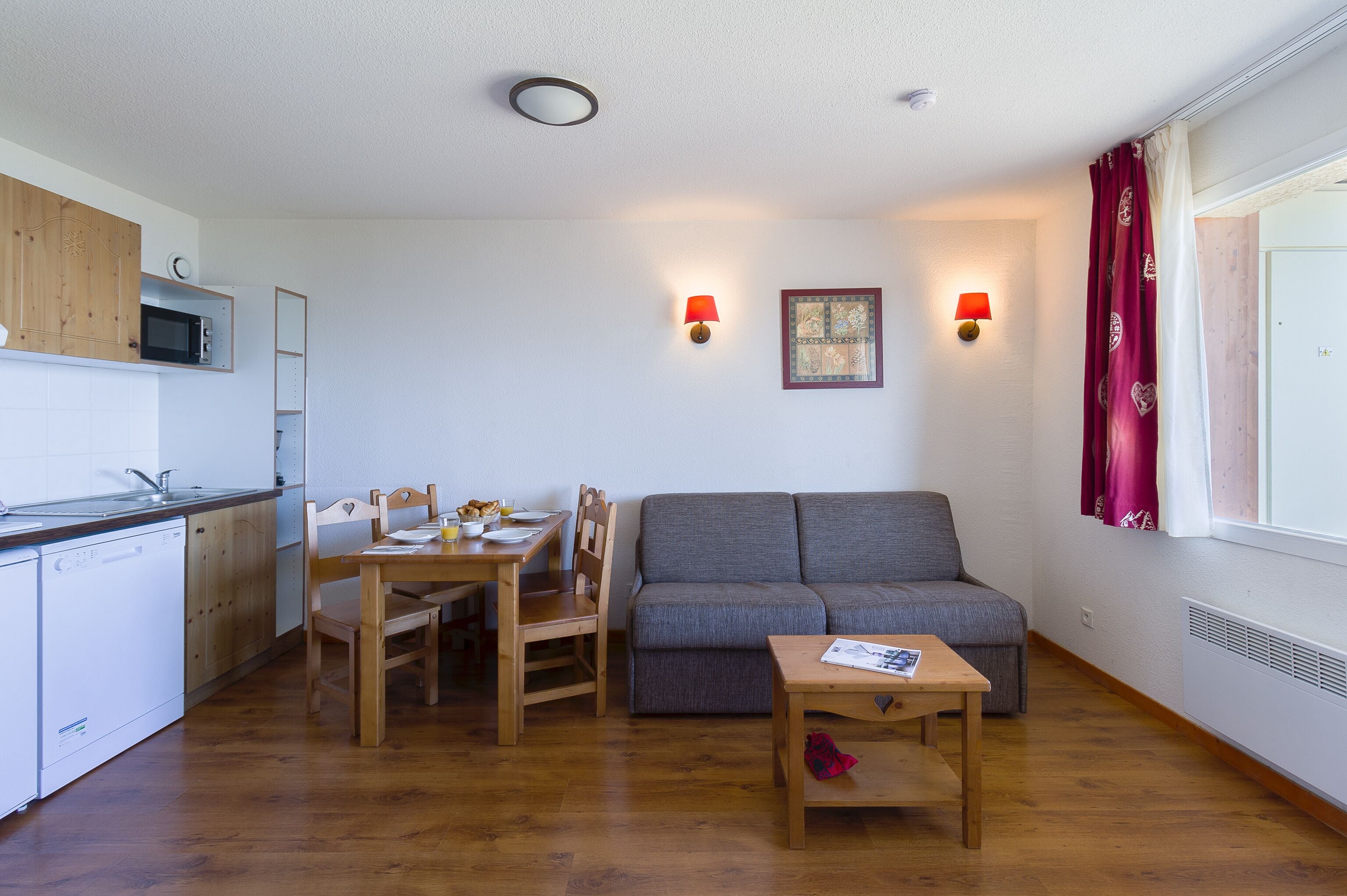 Un espace de vie compact comprenant un coin cuisine, un coin repas et un espace détente avec un canapé et une table.