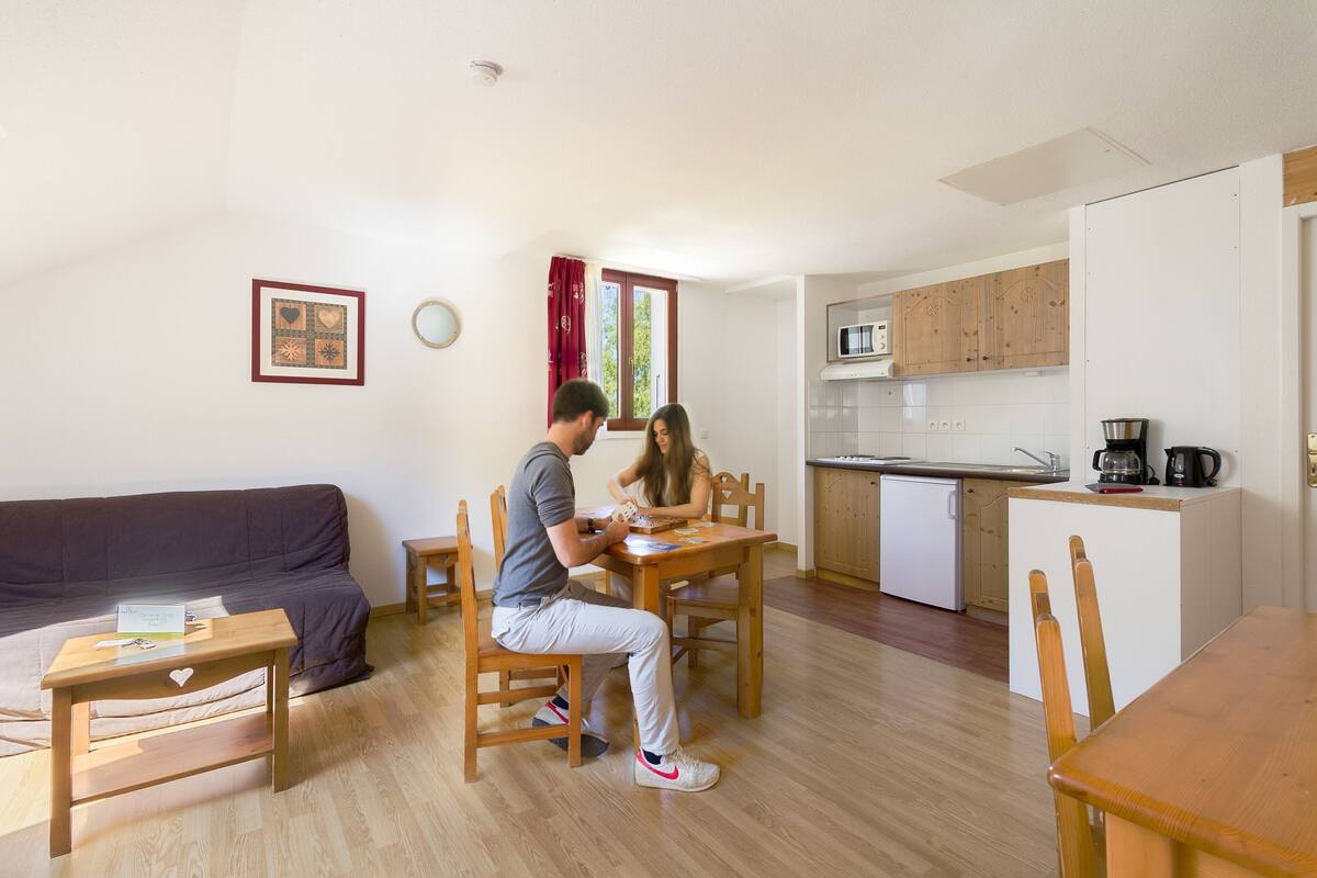 A compact living space with a dining area, kitchenette, and a sofa.
