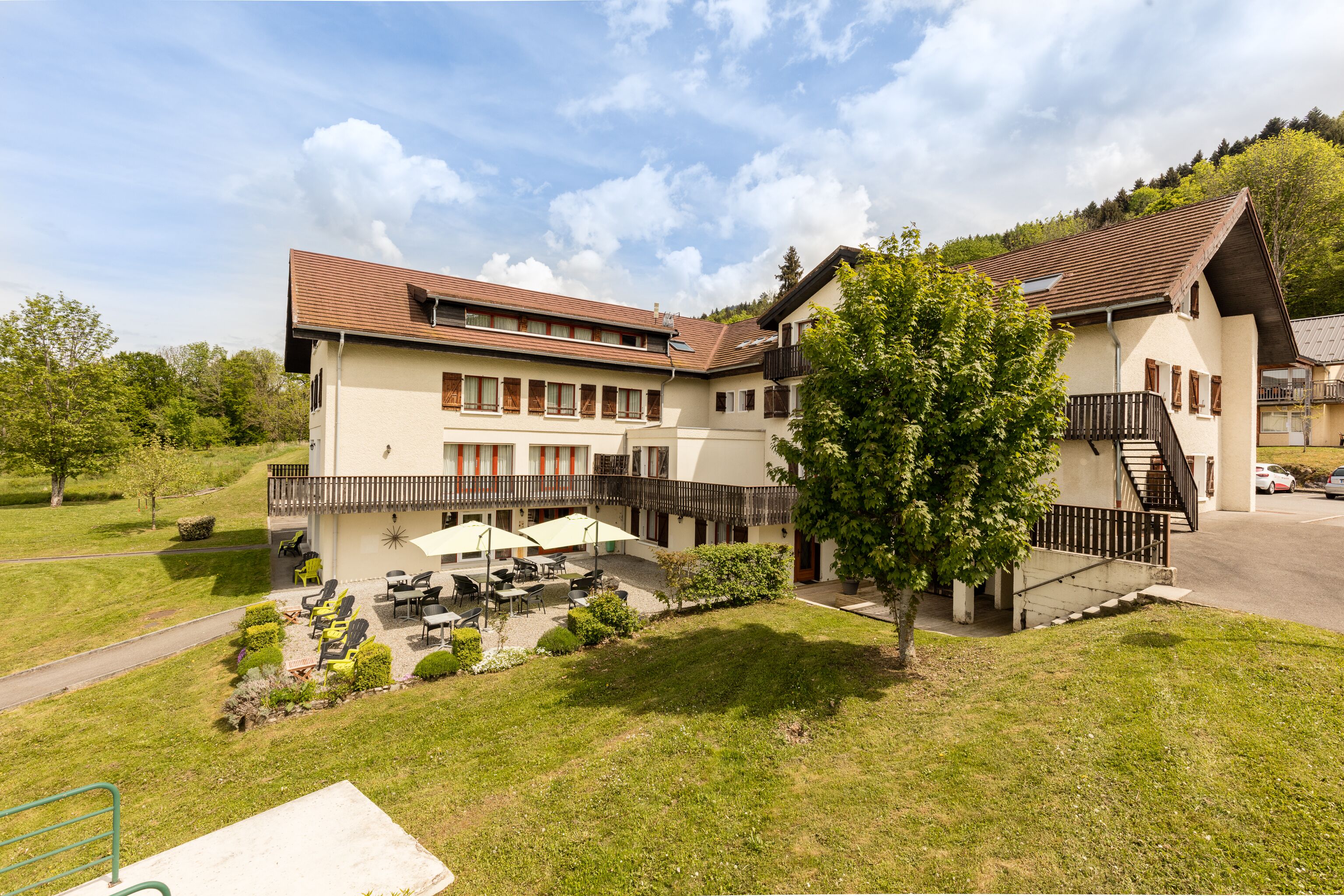 A two-story building with a patio area featuring outdoor seating and umbrellas.